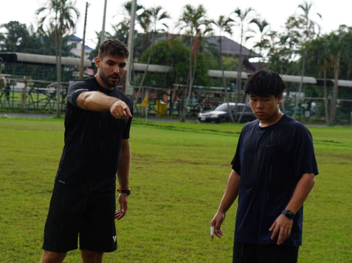 Entrenador dando instrucciones a jugadores jóvenes de fútbol en entrenamiento